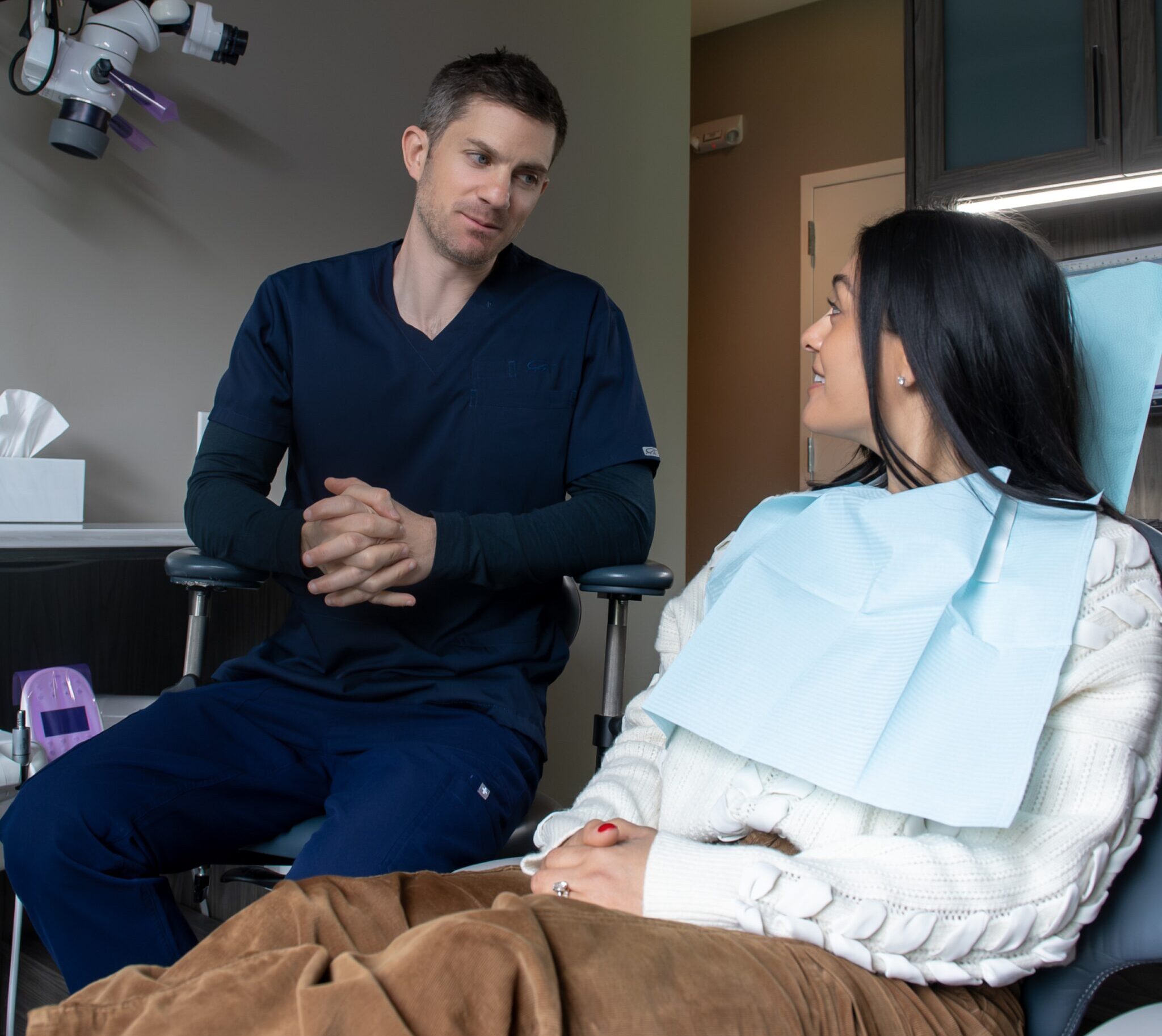 Endodontist discussing root canal treatment with a patient in the exam room